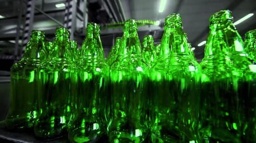 ligne de remplissage de bière dans une brasserie. Bouteilles en verre vert vides se déplaçant sur un tapis roulant dans une file d'attente a