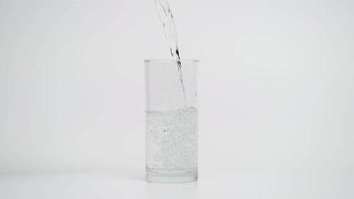 Cámara lenta de verter agua con gas en un vaso de 1000 fps sobre fondo blanco