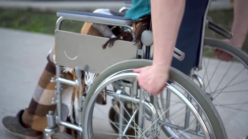 Young Man in a Wheelchair. A Man Rides in a Wheelchair Close-up Hand. Special Transport for the