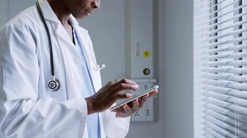 Seitenansicht eines afroamerikanischen Arztes mit digitalem Tablet im Krankenhaus 4k