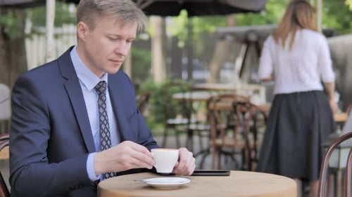 Businessman Drinking Coffee while Sitting in Outdoor Cafe