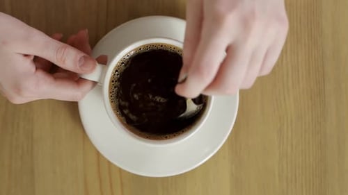 Köstlicher und aromatisierter heißer Kaffee, der sich nach dem Rühren in einer weißen Tasse dreht