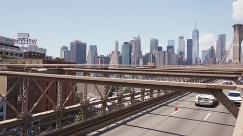 Traffic on the Brooklyn Bridge, with Manhattan's financial district in the distance on a sunny day,