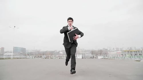 Guy with Briefcase in Hand in Business Suit Quickly Runs Away From Someone and Turns Back Around