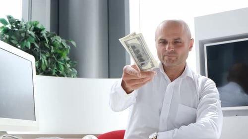 Man Stacks and Tosses Money at Office Desk