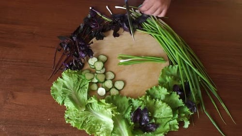 Women's Hands Cut Green Onions on a Wooden Round Cutting Board