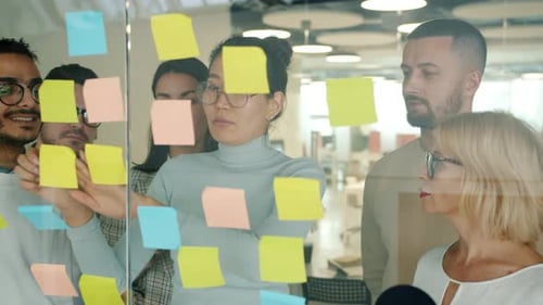 Business People Working with Sticky Notes in Office Using Glass Board Talking