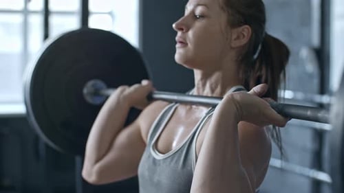 Athletic Woman Squatting with Weighted Barbell