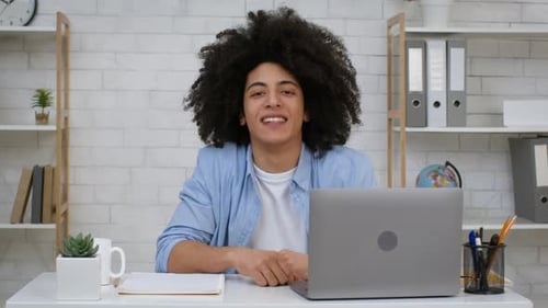 Smiling Young Adult Sitting at Desk with Laptop