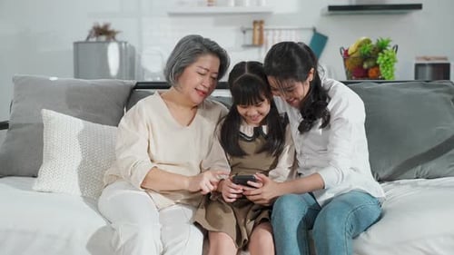 Three People Looking at Smartphone on Couch