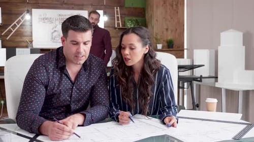 Businesswoman Talking with Her Contructor Engineer with Blueprints on the Office