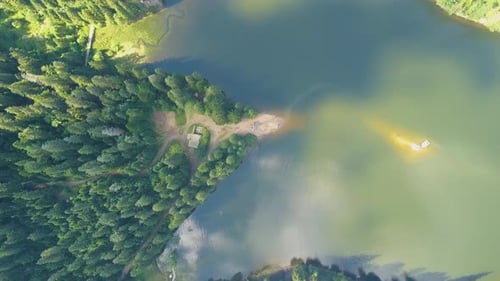 Top down aerial view of big lake with clear blue water between high mountain hills covered with