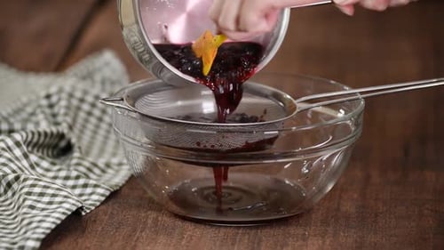 Woman Strains Berries Through a Sieve To Make Puree