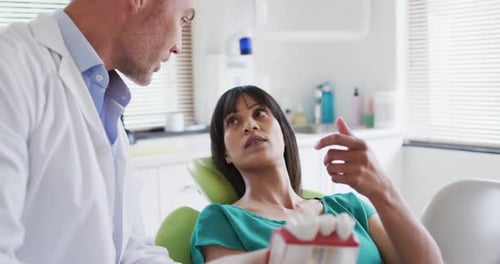 Caucasian male dentist examining teeth of female patient at modern dental clinic