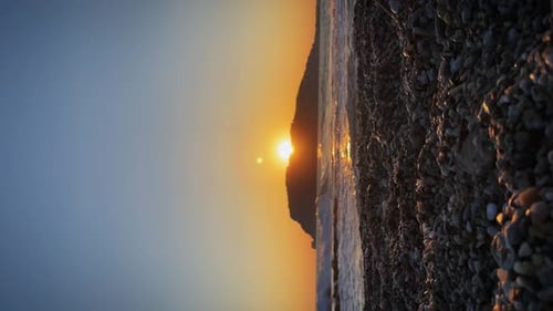 Sea sunset with silhouette of rocky coastline at horizon. Vertical video.