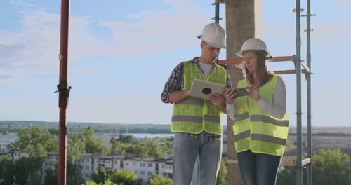 Ingenieure Baumeister Mann und Frau stehen mit einem Tablet-Computer auf dem Dach des Gebäudes