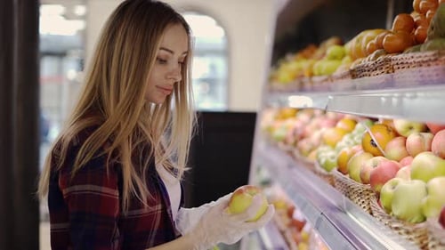 Woman in Glove Picks Fruits Apples in Basket in Supermarket