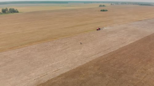 Aerial View of Tractor Tilling Large Rural Field