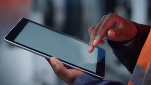 Unknown Man Hands Tapping Tablet Computer Digital Screen on Modern Factory