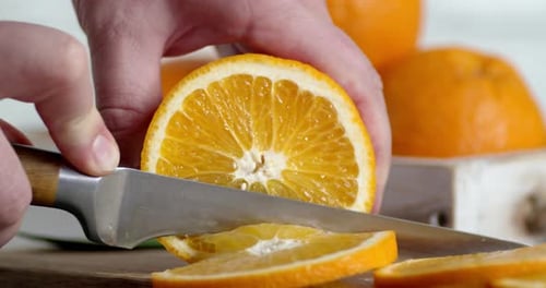 Male Hands Slicing Fresh Orange Into Round Slices.