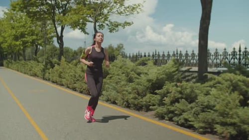 Sporty Female Jogging Along Running Path in Park