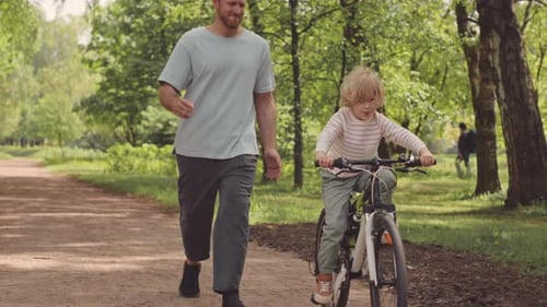 Little Boy Riding Bike Outdoors with Father