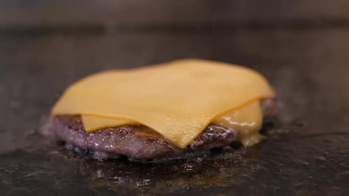 Cheeseburger Patty Sizzling on a Flat Top Grill