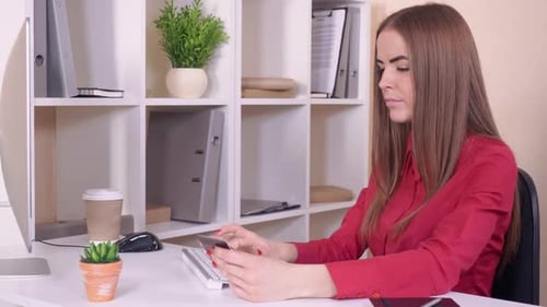 Woman Typing Credit Card Information at Desk