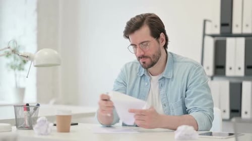 Man Writing and Crumpling Paper at Desk