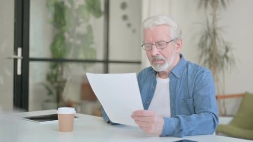 Senior Old Man Celebrating Success While Reading Documents in Office