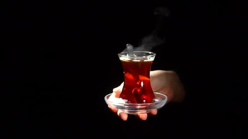 Frau bietet ein Glas Schwarztee an 2