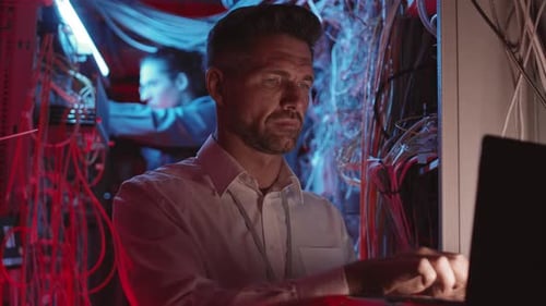 Man Typing on Laptop in Bright Data Center