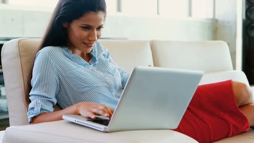 Woman Using Laptop on Couch with Credit Card