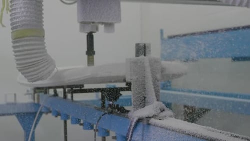 Surfboard being shaped by a machine in a workshop