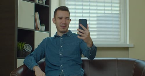 Man Waving During Video Call on Smartphone