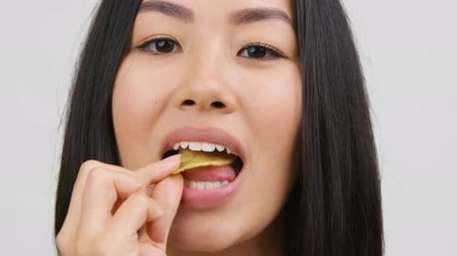 Young Adult Woman Eating Potato Chip, Close Up