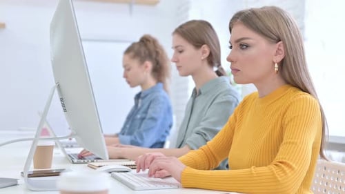 Junges Kreativteam arbeitet am Desktop und schaut in die Kamera
