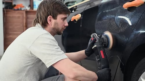 Man Polishing a Car with Power Buffer in Garage
