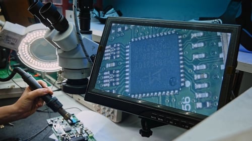 Technician Repairing Electronic Circuit Board at Workbench