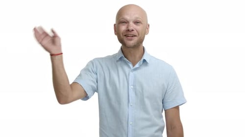 Friendly Cheerful Bald Man in Blue Shirt Waving Hand and Saying Hello Smiling and Greeting Person
