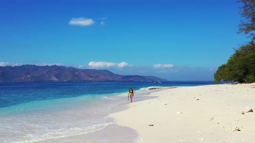 Happy Tourist Woman in Green Bikini Walking On the White Sand Beach holding snorkeling geatr With Cl