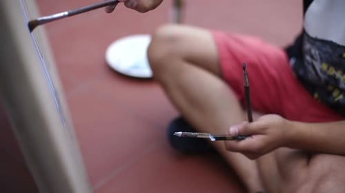 Young Adult Painting on Canvas Outside