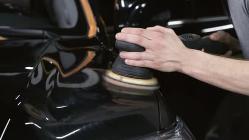 Man Polishing Car with Machine in Workshop