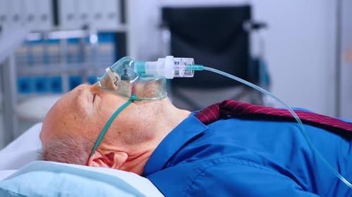 Senior Man in Hospital Bed with Oxygen Mask