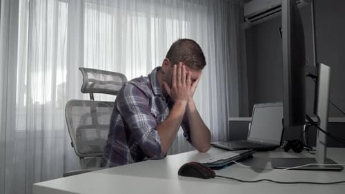 Verärgerter männlicher Freelancer sitzt vor seinen Computern