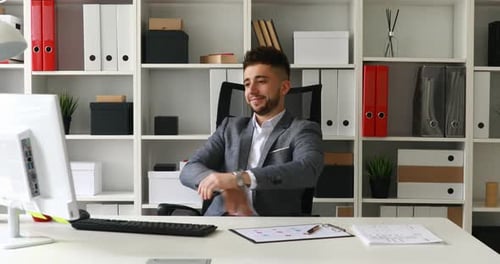 Junger Geschäftsmann dreht sich im Bürostuhl und freut sich über den Erfolg
