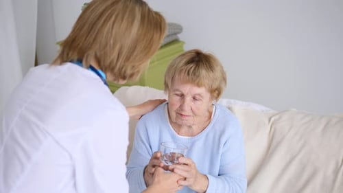 Nurse Gives Elderly Woman Glass of Water