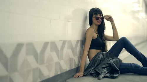 4K Portrait of Stylish Hispanic woman sitting in cross street tunnel in the city at night.