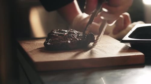Restaurant Cooking Chef Puts a Piece of Meat on the Board
