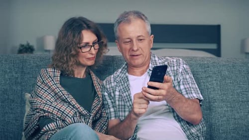 Couple Looking at Smartphone Together on Sofa